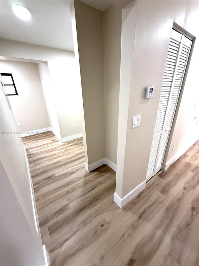 hallway with light wood-style flooring and baseboards