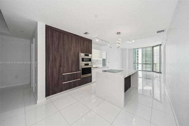 kitchen featuring visible vents, modern cabinets, a center island, light countertops, and backsplash