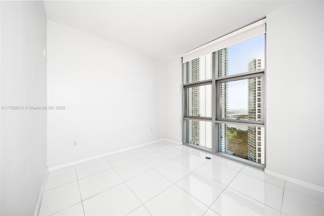 unfurnished room featuring light tile patterned floors, baseboards, and a wall of windows