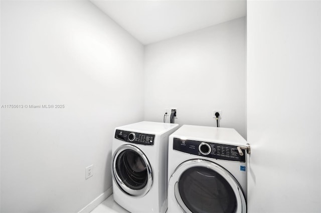 clothes washing area with laundry area, baseboards, and washer and clothes dryer