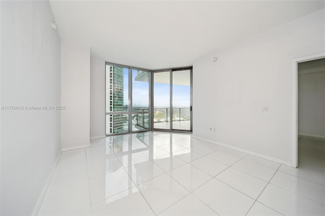 unfurnished room featuring expansive windows, baseboards, and light tile patterned floors