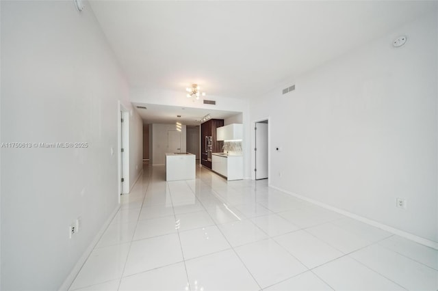 unfurnished living room with visible vents, baseboards, and light tile patterned floors