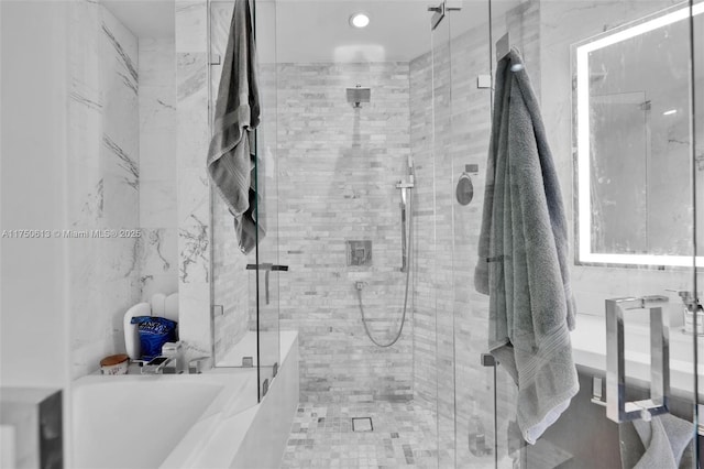 bathroom with a shower stall and a bathing tub