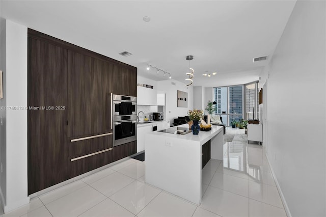 kitchen featuring a kitchen island, visible vents, white cabinetry, light countertops, and pendant lighting