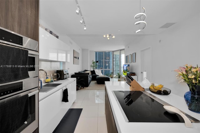 kitchen featuring light tile patterned floors, expansive windows, black electric cooktop, light countertops, and a sink