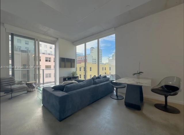 living area featuring expansive windows, concrete floors, and baseboards