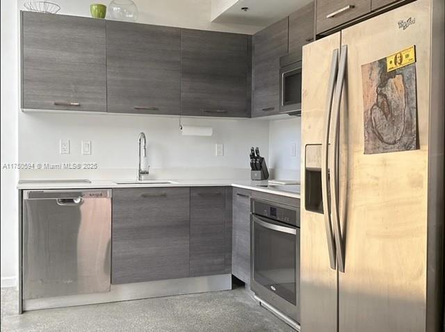 kitchen featuring modern cabinets, appliances with stainless steel finishes, light countertops, and a sink