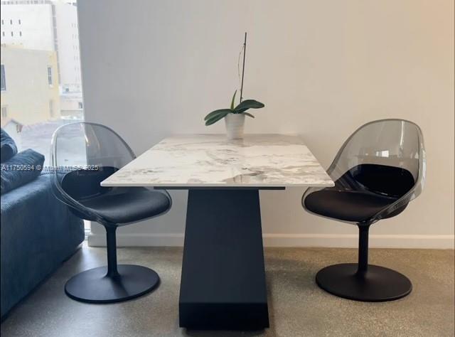 dining space featuring baseboards and speckled floor