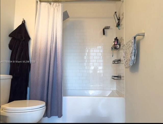 bathroom featuring shower / bathtub combination with curtain and toilet