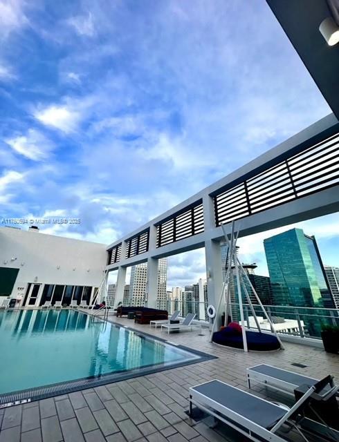 community pool with a patio area, a city view, and a pergola