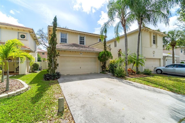 traditional-style home with a garage, a front lawn, concrete driveway, and stucco siding