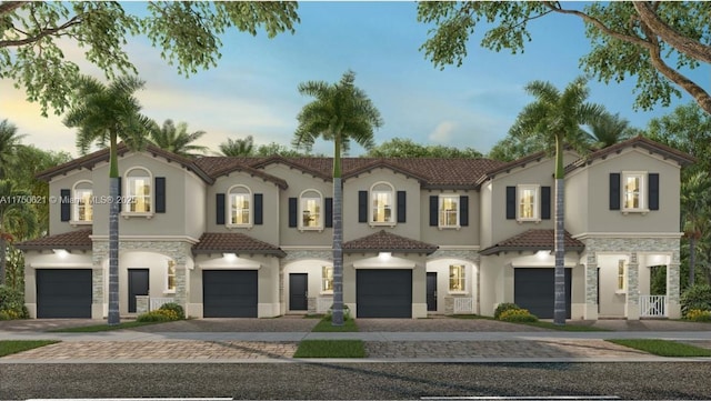 mediterranean / spanish-style house featuring a garage, a tiled roof, stone siding, decorative driveway, and stucco siding