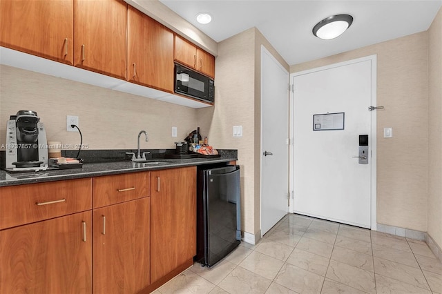 kitchen featuring dark stone countertops, brown cabinets, a sink, and black appliances