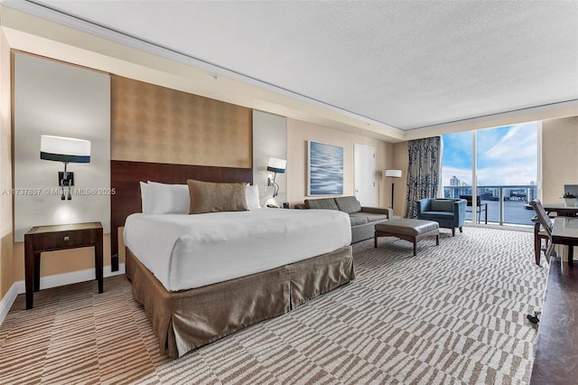 carpeted bedroom featuring a water view, expansive windows, a textured ceiling, access to outside, and baseboards