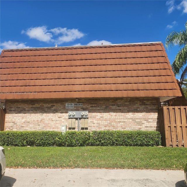 exterior space with mansard roof and brick siding