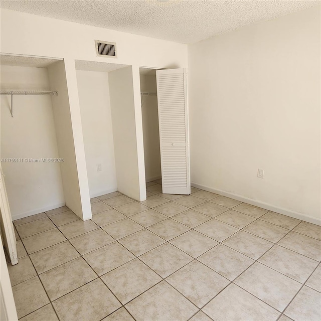 4149 Wimbledon Dr Unit 4149, Cooper City, FL 33026 - unfurnished bedroom with a textured ceiling, light tile patterned floors, and two closets