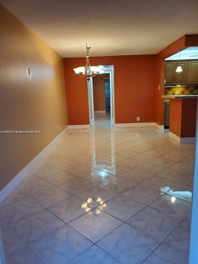 interior space with a notable chandelier, a textured ceiling, and baseboards