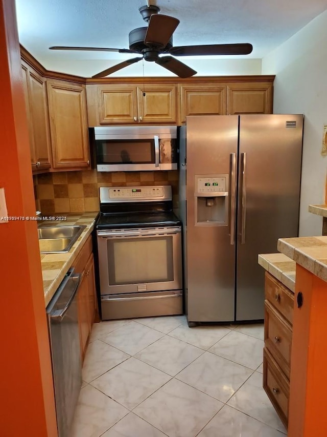 kitchen featuring brown cabinetry, stainless steel appliances, and a sink