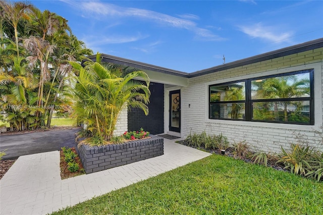 property entrance with brick siding and a lawn