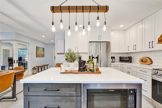 kitchen with a center island, decorative light fixtures, stainless steel appliances, backsplash, and white cabinetry