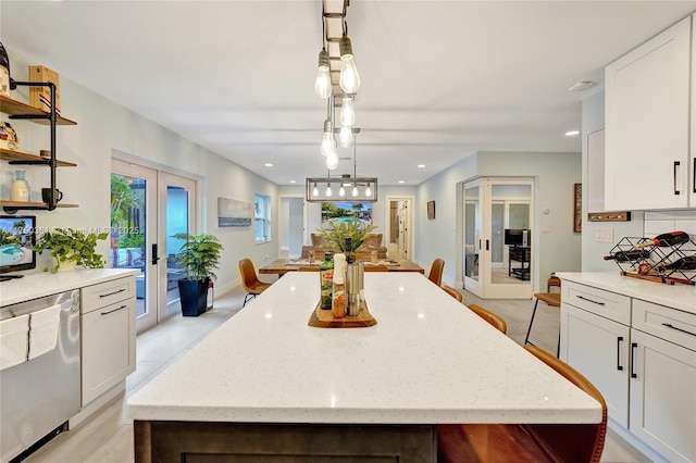 kitchen with pendant lighting, french doors, white cabinets, and stainless steel dishwasher