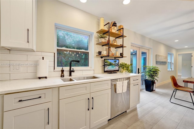 kitchen with a sink, stainless steel dishwasher, light stone countertops, open shelves, and tasteful backsplash