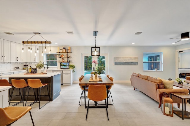 kitchen featuring pendant lighting, light countertops, backsplash, white cabinetry, and a kitchen bar