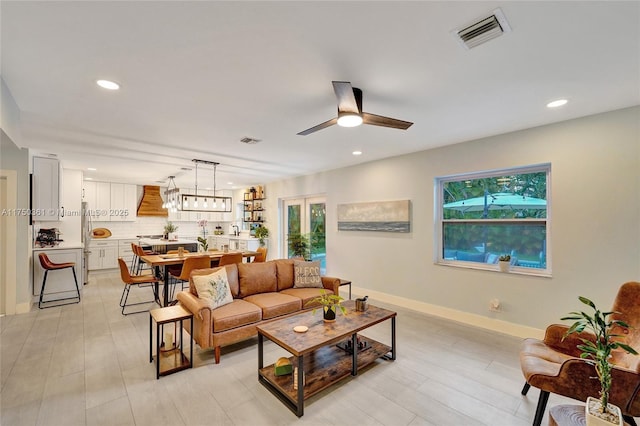 living room featuring baseboards, visible vents, and a healthy amount of sunlight