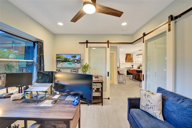 office area with a ceiling fan, recessed lighting, light wood-style flooring, and a barn door