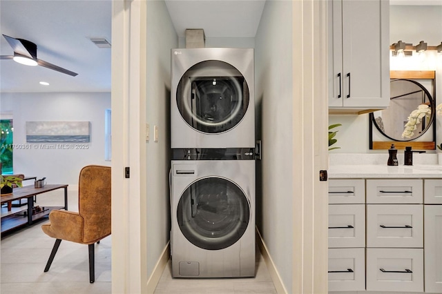 clothes washing area featuring laundry area, visible vents, baseboards, a ceiling fan, and stacked washing maching and dryer