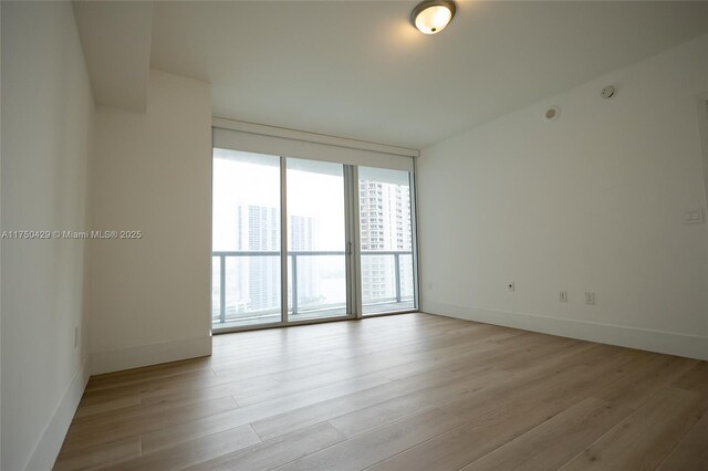 495 Brickell Ave Unit 2102, Miami, FL 33131 - spare room with baseboards, light wood-style floors, and floor to ceiling windows