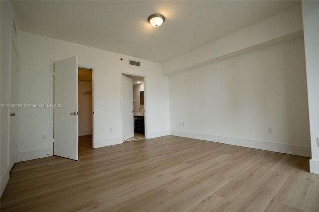 495 Brickell Ave Unit 2102, Miami, FL 33131 - unfurnished bedroom with light wood finished floors, baseboards, visible vents, connected bathroom, and a walk in closet