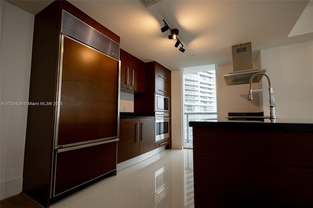 495 Brickell Ave Unit 2102, Miami, FL 33131 - kitchen with dark countertops, a sink, track lighting, built in appliances, and a wall of windows