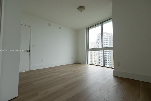 495 Brickell Ave Unit 2102, Miami, FL 33131 - empty room with light wood-type flooring, a view of city, floor to ceiling windows, and baseboards