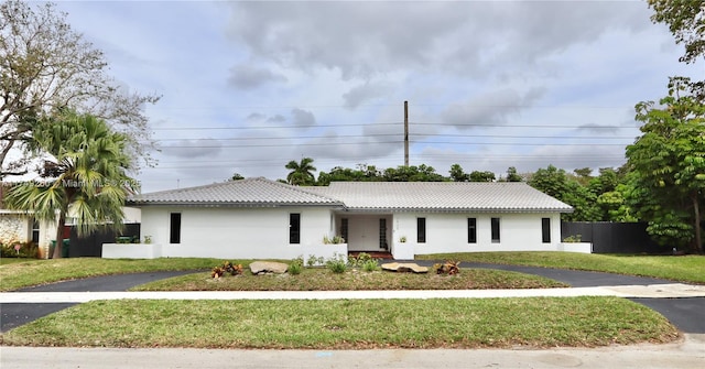 single story home featuring stucco siding, a front yard, fence, driveway, and a tiled roof