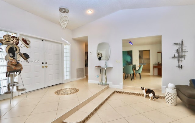 tiled foyer with high vaulted ceiling, baseboards, and visible vents