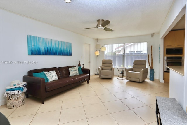 living area featuring a ceiling fan, a textured ceiling, and light tile patterned floors