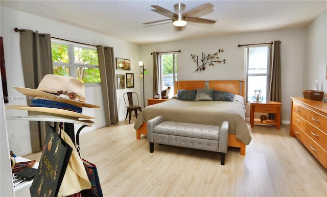 bedroom with ceiling fan, light wood-style flooring, and baseboards