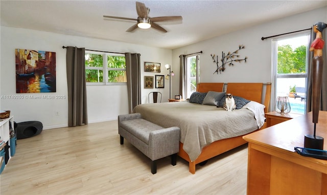 bedroom with a ceiling fan, baseboards, and light wood finished floors