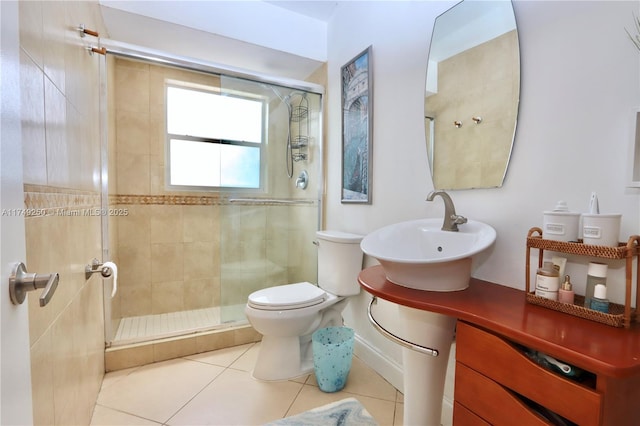 bathroom featuring toilet, a stall shower, a sink, and tile patterned floors