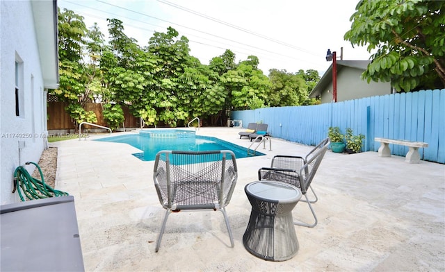 view of pool featuring a fenced backyard, a pool with connected hot tub, and a patio