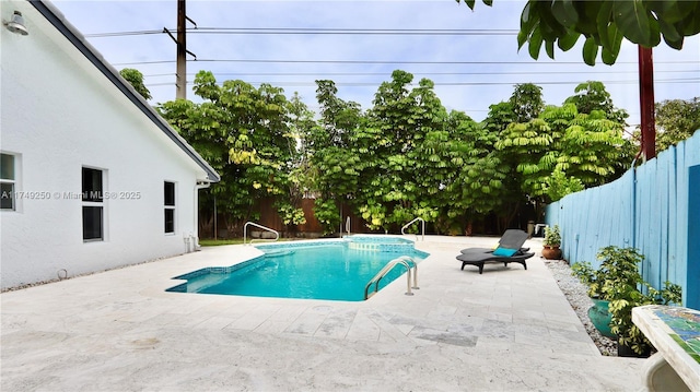 view of swimming pool with a fenced backyard, a pool with connected hot tub, and a patio