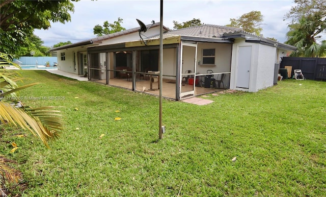 rear view of property featuring a fenced in pool, a yard, stucco siding, a sunroom, and fence