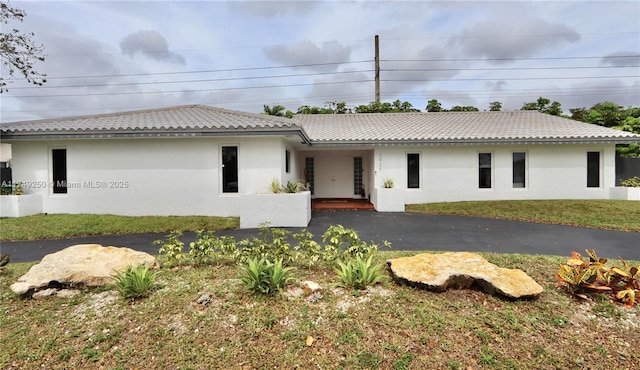 view of front of property featuring a tiled roof, a front yard, and stucco siding