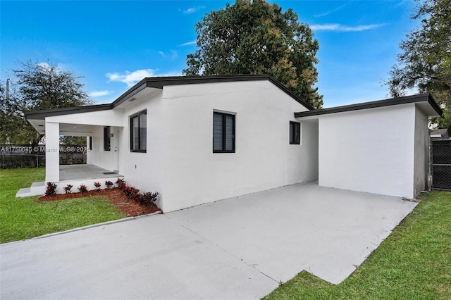 view of property exterior with a lawn, fence, and stucco siding