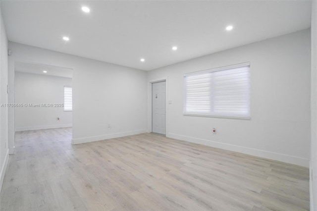 empty room with light wood-style floors, recessed lighting, and baseboards