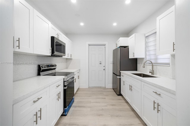 kitchen featuring stainless steel appliances, a sink, and white cabinetry