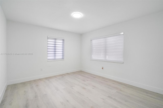 spare room featuring light wood finished floors and baseboards