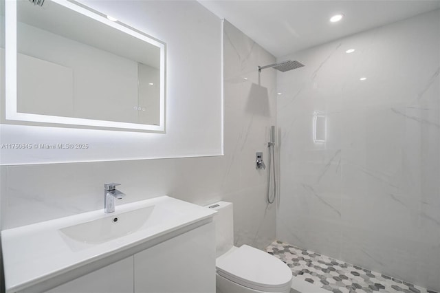 bathroom with a marble finish shower, vanity, and toilet