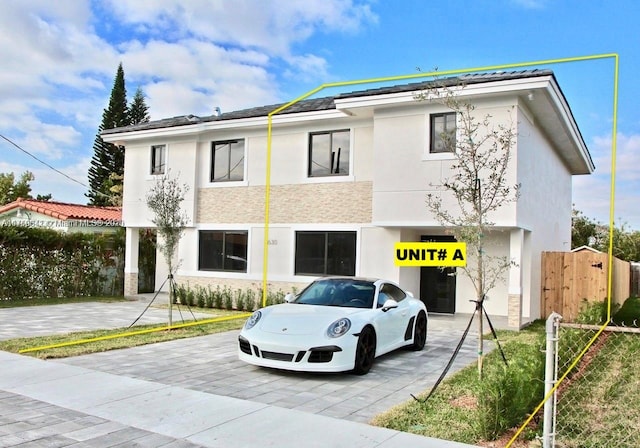 view of building exterior featuring decorative driveway and fence